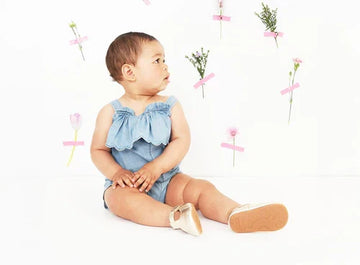Toddler in studio shot seated looking to its left, background of sprigs of flowers