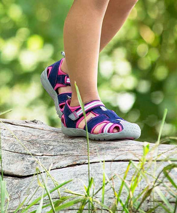 Figure walking along a log wearing Pediped Sahara barefoot sandals