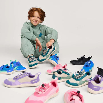 Childin tracksuit in studio seated with array of Reima barefoot trainers