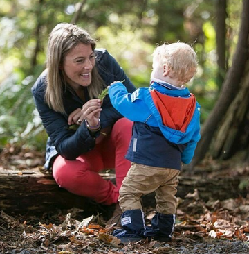 Woman and toddler in woods looking at a leaf
