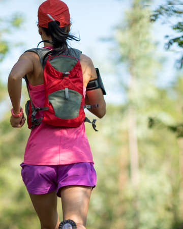 Runner wearing pink and red from rear in woodland setting