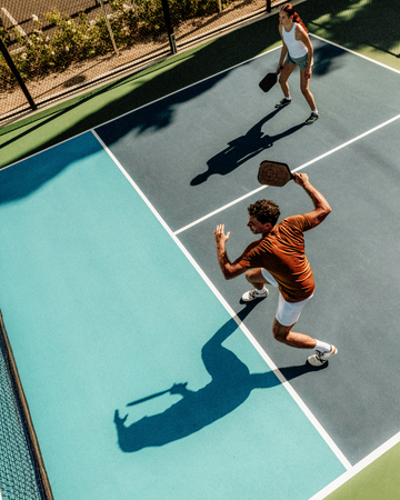 Two tennis players on a very sunny outdoor court, strong shadows feature
