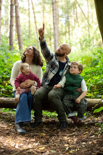 Family in woodland setting pointing at sky in their barefoot shoes from Happy Little Soles