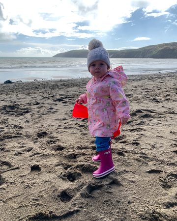 Child in pink coat on a beach 
