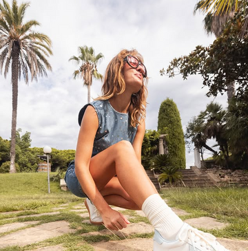 Sunny day, palm trees, woman in shorts wearing Victoria Barefoot trainers.