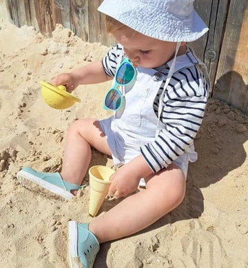 Child playing in the sand wearing Boatilus Cloggy Sandals - Pastel Green White.