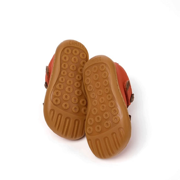 Pair of Camper Kids First Peu Boots in orange, sole view.