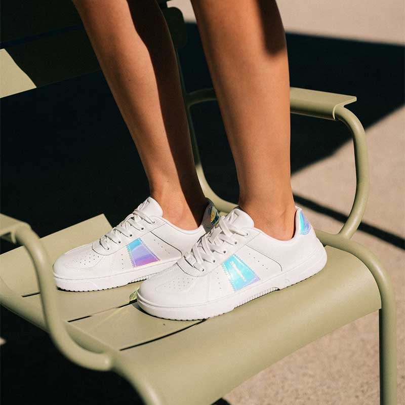 Person wearing Be Lenka Adults Barebarics Trainers Icara - White and Pastel Iridescent standing on a chair