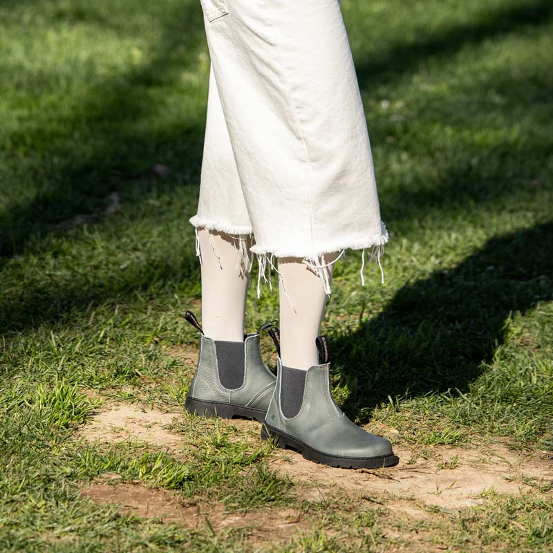 Person wearing El Naturalista Barefoot Alpine Nomada Chelsea Boots - Petrol with white trousers.