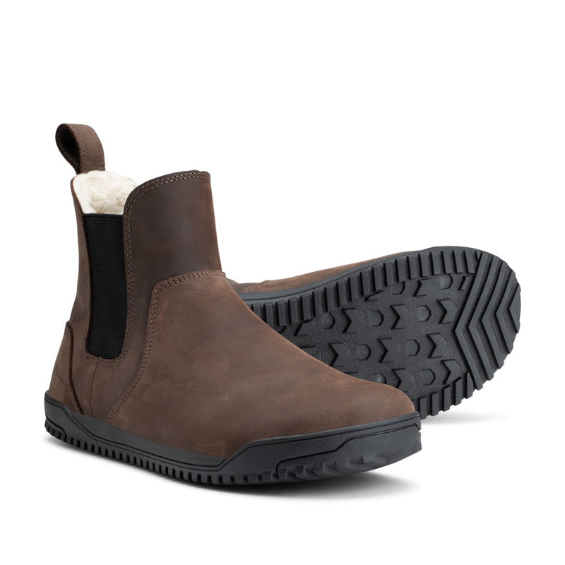 Pair of Xero Women's Lined Chelsea Boots Ridgeway - Brown, one on its side slightly showing the sole view and the other angled, showing the outer side and front view.