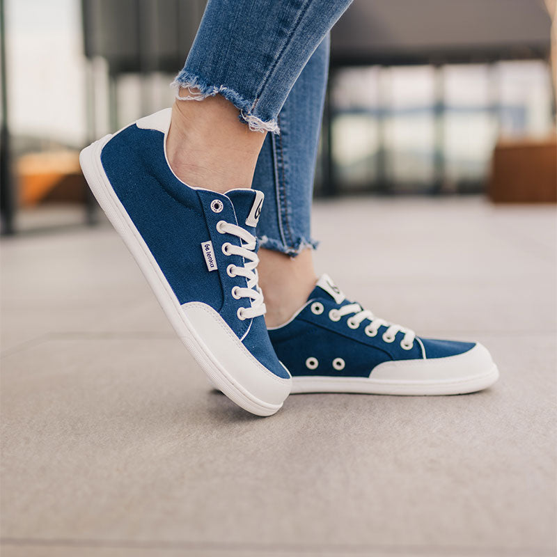 Person wearing Be Lenka Adults Trainers Rebound - Dark Blue and White with denim jeans, side view