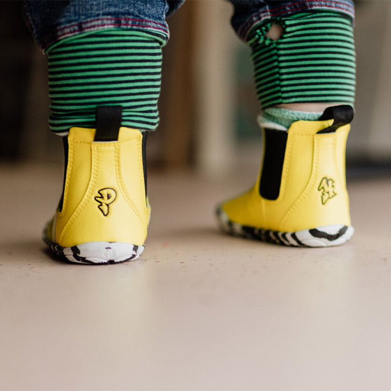 Child wearing PaperKrane Kids Sunny Chelsea Boots - Yellow, rear view.