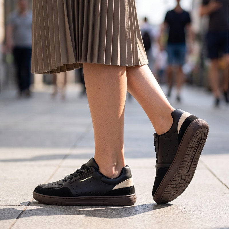Person wearing Be Lenka Adults Barebarics Trainers Wave 2.0 - Black and Dark Brown, side view.