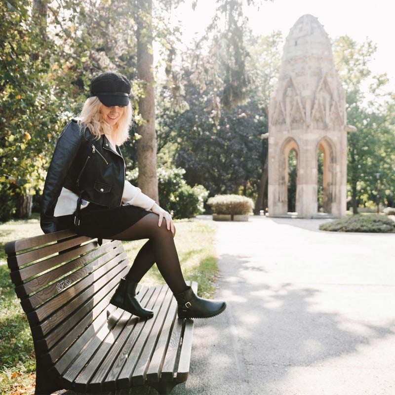 Person wearing Be Lenka Adults Boots Diva - All Black with black tights sat on a bench