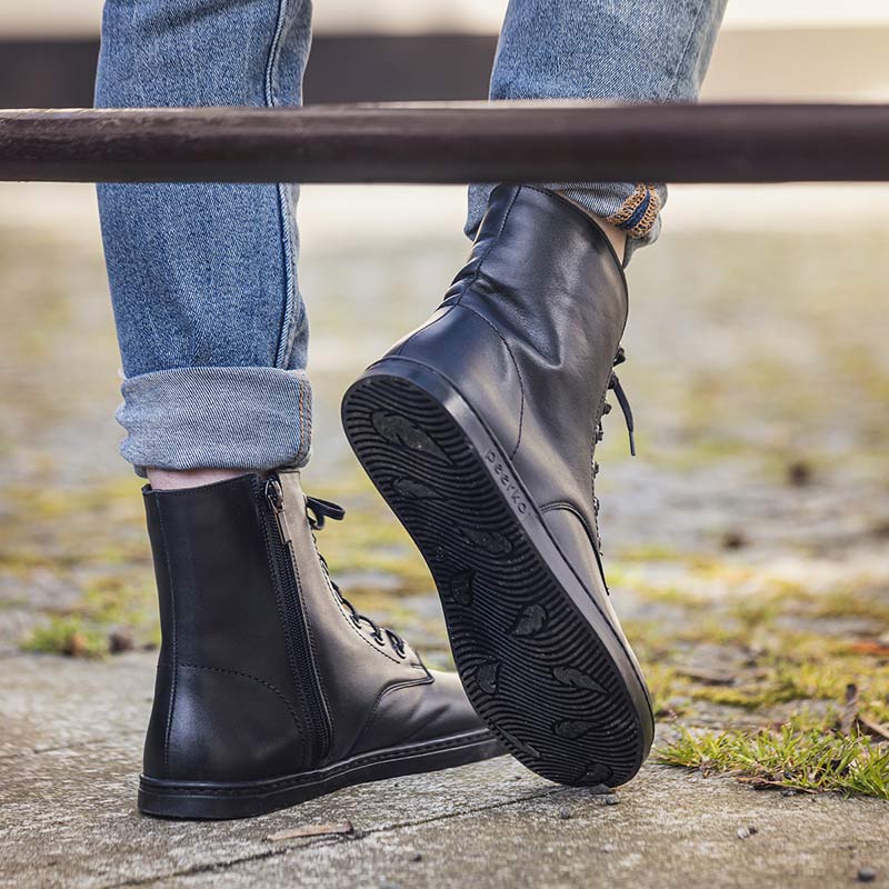 Person wearing Peerko Adults Boots Breeze - Black with denim jeans, rear and sole view.