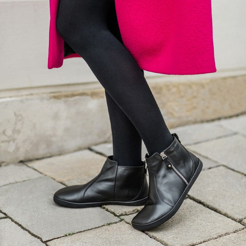Person wearing Shapen Women's Ivy 2.0 Ankle Boots - Black with black tights, inner and outer side view.