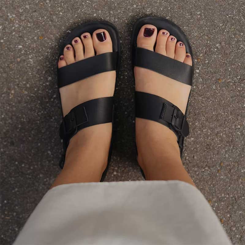 Person wearing Groundies Adults Kos Sandals in black.