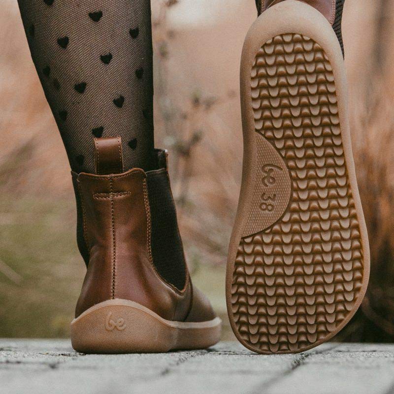 Person wearing Be Lenka Adults Boots Entice Neo - Dark Brown with patterned black tights, rear view
