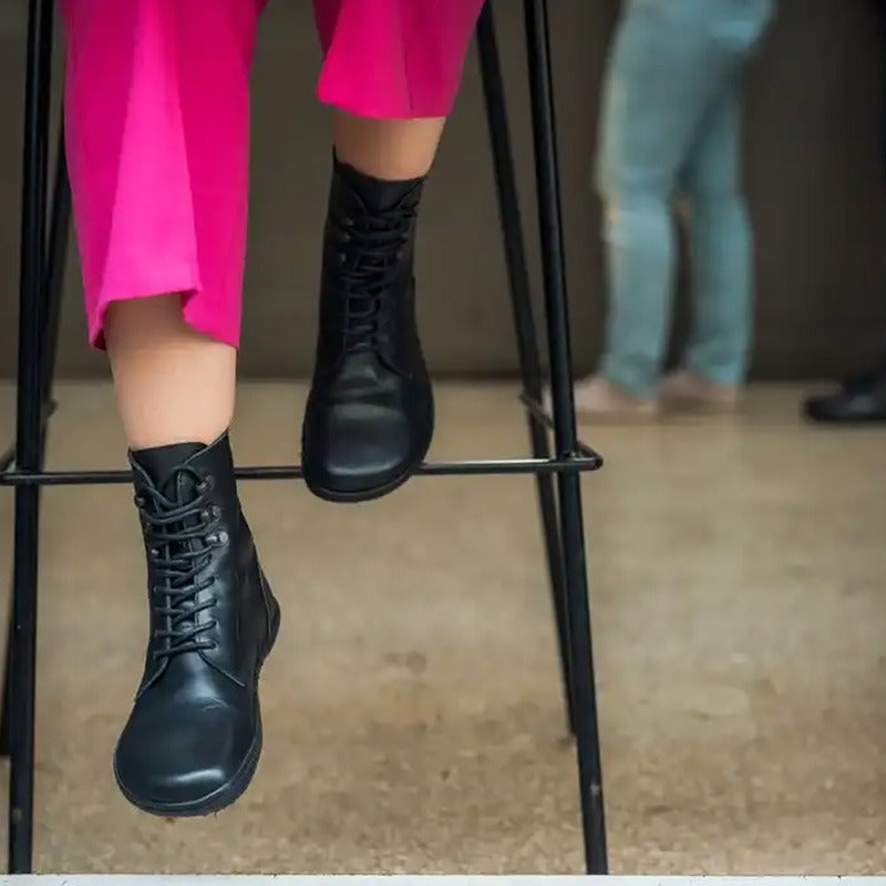 Person wearing Angles Women's Leather Boot Orpheus - Black with pink trousers