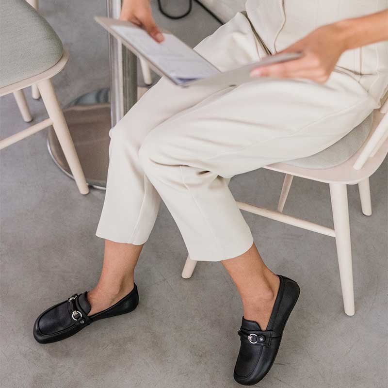 Person wearing Shapen Women's Versa 2.0 Loafers - Black with white trousers.