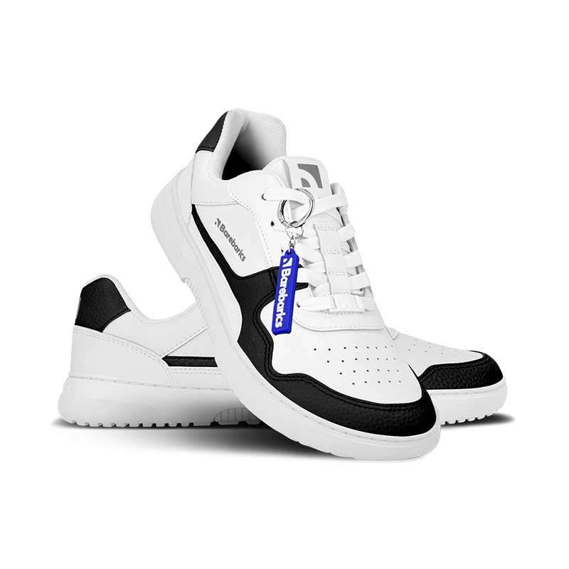 Pair of Be Lenka Adults Barebarics Leather Trainers Zing - White and Black, one angled and leaning showing the outer side and Barebarics keyring, the other partially showing the inner side