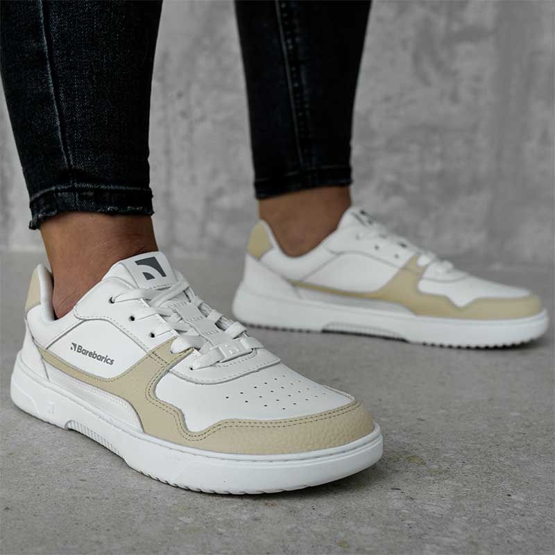 Person wearing Be Lenka Adults Barebarics Leather Trainers Zing - White and Cream with jeans