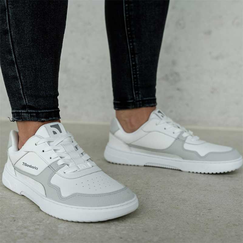 Person wearing Be Lenka Adults Barebarics Leather Trainers Zing - White and Light Grey with black jeans